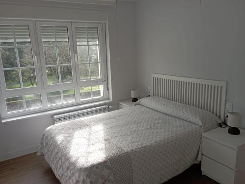 Un dormitorio con dos camas y dos ventanas. en La Fuente, en Luarca