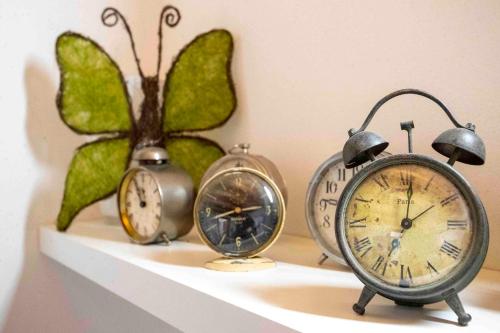 three clocks on a shelf with a butterfly on it at The clock house -Centro storico- in Clusone