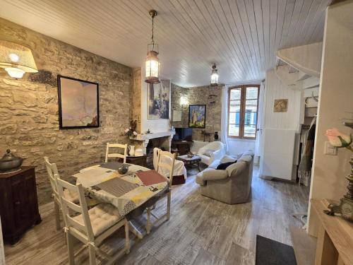 - un salon avec une table à manger et un mur en pierre dans l'établissement Charme au cœur de Beynac avec climatisation et parking privé - FR-1-616-462, à Beynac-et-Cazenac