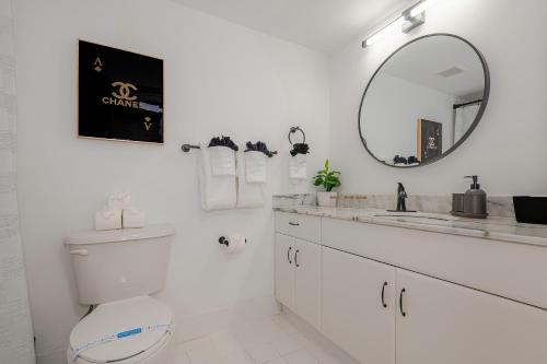 a white bathroom with a toilet and a mirror at Warm and Comfy Studio in Miami