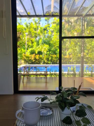 a table with a coffee cup and a plant in front of a window at The Zentuary - House with pool in Amadeo