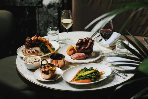 a table with plates of food and glasses of wine at Stock Exchange Hotel, Manchester, Autograph Collection in Manchester
