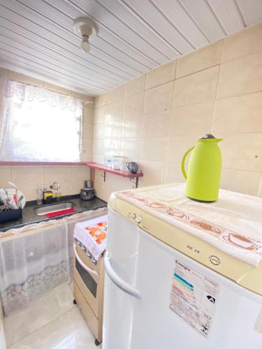 a kitchen with a green pitcher on top of a refrigerator at Suíte Pé na Areia in Arraial do Cabo