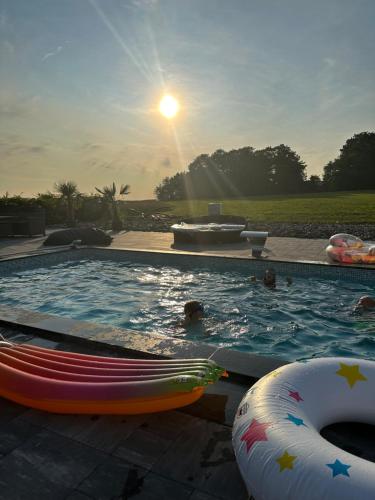 a swimming pool with people in it with the sun setting at Cozy home in quiet neighborhood in Ängelholm