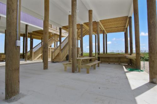a building with wooden pillars and benches in it at Spacious Beachfront 5BR with Gorgeous Ocean views - Blue Footed in Bolivar Peninsula