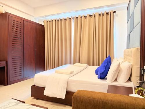 a bedroom with a bed with white sheets and blue pillows at Negombo Ocean Breeze - ShoresEdge Luxury Apartments in Negombo