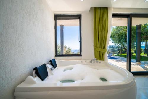 a large white bath tub in a room with windows at KaşKalkan Deniz manzaralı Havuzlu Bahçeli Villa in Kas