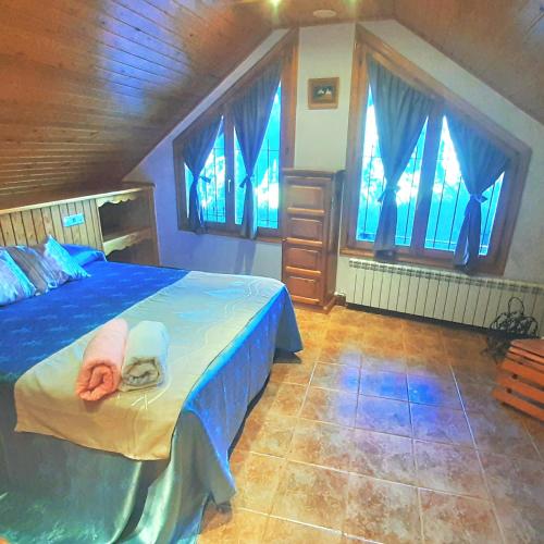 a bedroom with a bed with blue sheets and windows at Ático-Duplex Basa la Mora in Saravillo