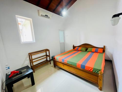 a bedroom with a bed and a window and a table at Warusha Villa in Hikkaduwa