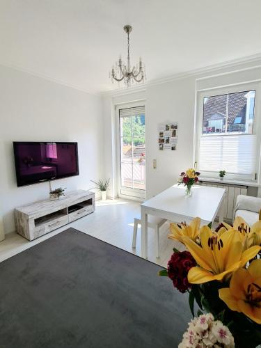 a living room with a television and a table with flowers at Wohnung mit Blick auf den Rheingrafenstein in Bad Kreuznach