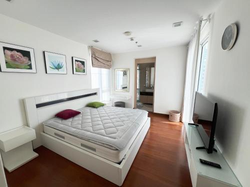 北芭堤雅The Palm Wongamat - 2BR Luxury Beachfront Suite - Ocean View的一间带床和平板电视的卧室
