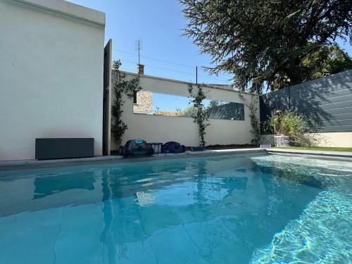 - une piscine en face d'un mur blanc dans l'établissement Chambres d'hôte, à Châteauneuf-de-Gadagne