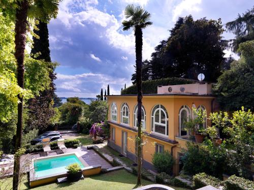 a house with a palm tree and a swimming pool at Villa Ella con Depandance in Gardone Riviera
