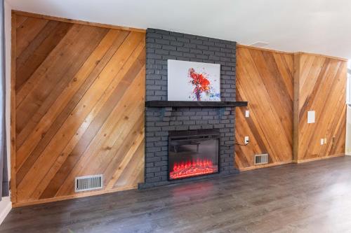 a living room with a brick fireplace with wooden walls at Perfect Getaway 3BR 3BA Home Close to Parks and Shopping in Ballwin