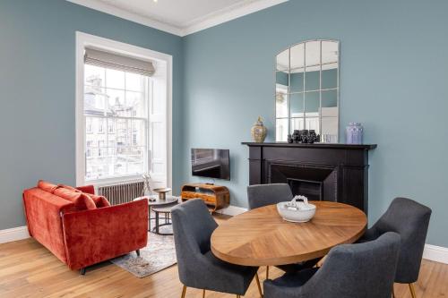 a living room with a table and chairs and a fireplace at Dragon Suites Luxury Apartments at 9 Albyn Place in Edinburgh