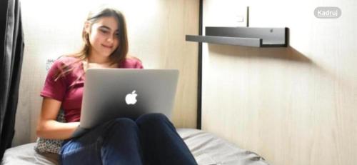 a woman sitting on a bed with a laptop at ONRest Hostel Centrum Żytnia 8 FaktVat in Kielce