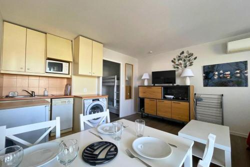 una cucina con un tavolo bianco e sedie in una cucina di Cigales de la Mer - climatisé, vue mer et parking a Le Grau-du-Roi