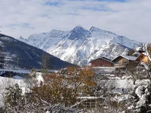 a snow covered mountain with a house in the foreground at Le Petit Rêve in Aosta