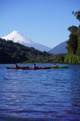 a group of people kayaking on a lake with a mountain at Entre Volcanes Lodge in Ensenada