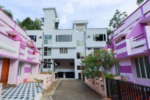 an apartment complex with pink and white buildings at Super Collection O Companion Leisure Homes in Kovalam