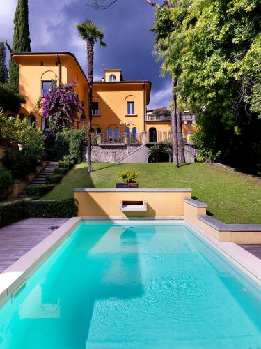 a swimming pool in front of a house at Villa Ella con Depandance in Gardone Riviera