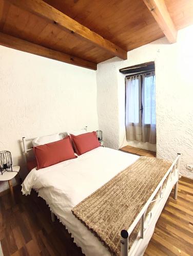 une chambre avec un lit avec des oreillers rouges et une fenêtre dans l'établissement Maison typique de village Corse , 10 min aéroport et de la mer, à Prunelli-di-Casacconi