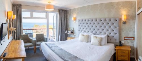 a hotel room with a large bed and a large window at The Cottage Hotel in Hope-Cove