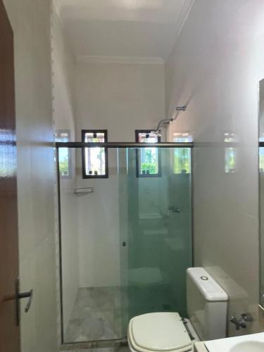 a bathroom with a toilet and a glass shower at Espaço Festa Campos in Campos dos Goytacazes