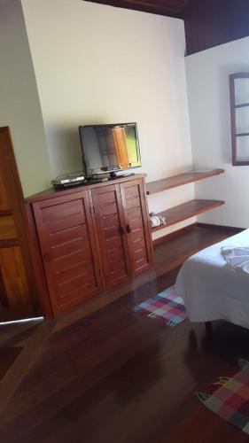 a bedroom with a tv on top of a wooden dresser at Pousada Bela Mauá in Itatiaia