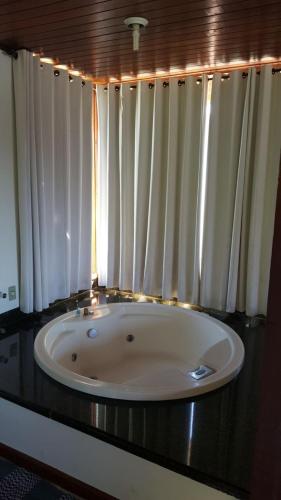 a bath tub in a bathroom with white curtains at Pousada Bela Mauá in Itatiaia