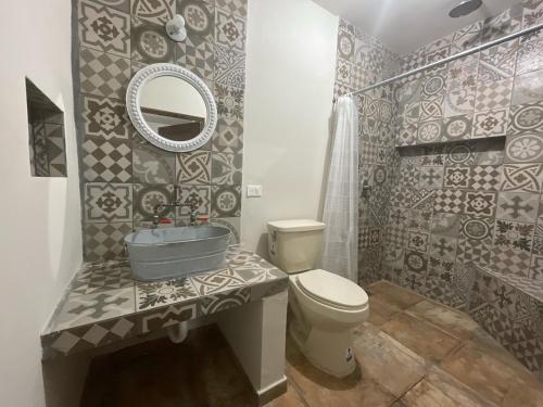 een badkamer met een wastafel, een toilet en een spiegel bij Finca El Fraile in Monterrey