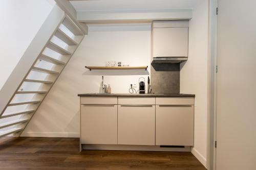 a kitchen with white cabinets and a staircase at HOLT Hotel in Nijmegen