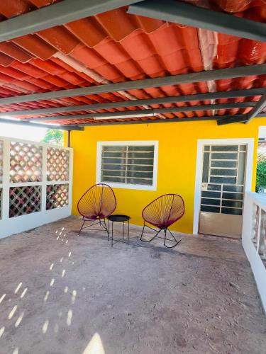 two chairs and a table in front of a yellow wall at Casa en el Centro de Mérida, 5 habitaciones y 3 baños, ideal para grupos in Mérida