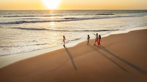 three people walking on the beach at sunset at Dreams Estrella del Mar Mazatlan Golf & Spa Resort - All Inclusive in Mazatlán