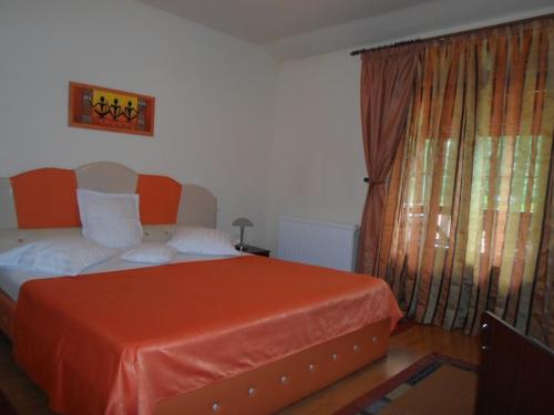 een slaapkamer met een bed met een oranje deken bij Pensiunea Speranta in Sovata