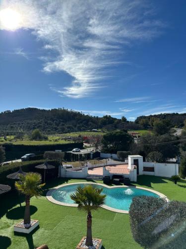 a resort with a swimming pool and palm trees at Mirador De La Vega De Cazalla in Cazalla de la Sierra