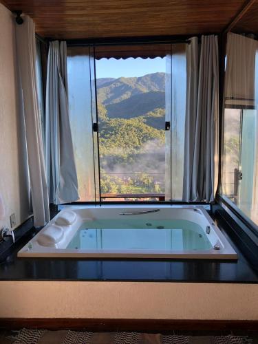 a bath tub in a room with a large window at Pousada Bela Mauá in Itatiaia