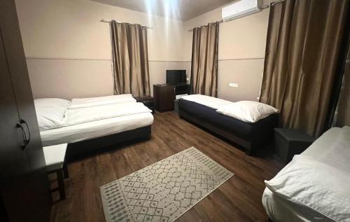 a small room with two beds and a television at OP-ART Étterem és Panzió in Monor