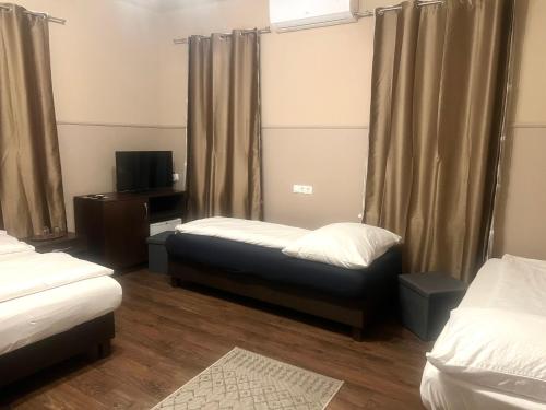 a room with two beds and a tv and curtains at OP-ART Étterem és Panzió in Monor