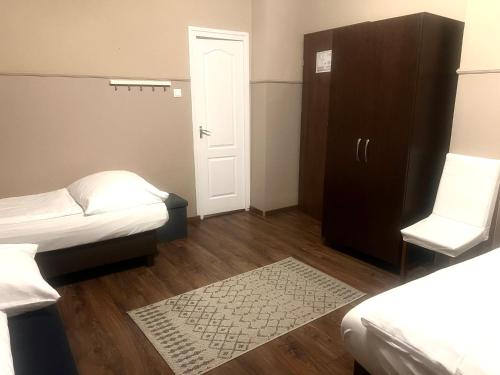 a room with two beds and a cabinet and a rug at OP-ART Étterem és Panzió in Monor