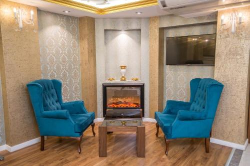 a living room with two blue chairs and a fireplace at Ruba Palace Thermal Hotel in Bursa