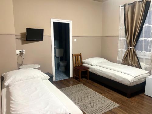 a small room with two beds and a mirror at OP-ART Étterem és Panzió in Monor