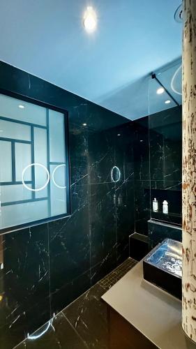 une salle de bain noire avec un lavabo et un miroir dans l'établissement Loft moderne Saint-Ambroise, à Paris