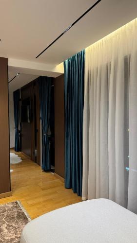 a bedroom with blue curtains and a room with a bed at Stayinn Emerald Shkoder in Shkodër