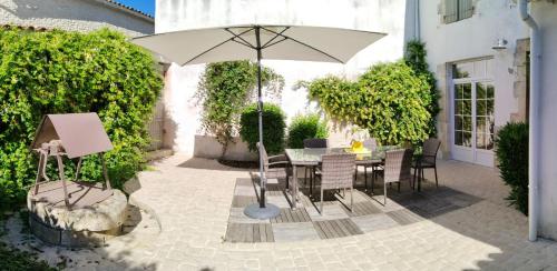 a patio with a table and an umbrella at île de Ré , maison de ville typique rétaise au Bois-Plage in Le Bois-Plage-en-Ré