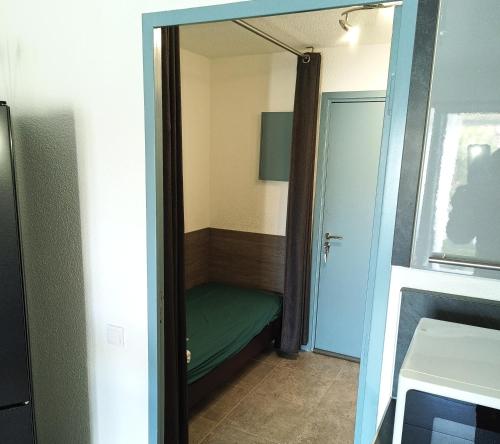Cette petite chambre comprend un lit vert et un miroir. dans l'établissement Logement plage, à Saint-Cyprien