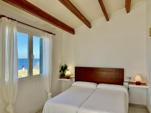 a white bedroom with a bed and a window at Villa Victor in Cala en Blanes