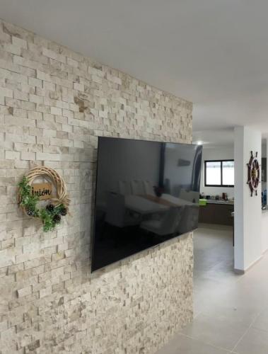 ConkalにあるItzamná Houseのレンガ壁に設置された薄型テレビ