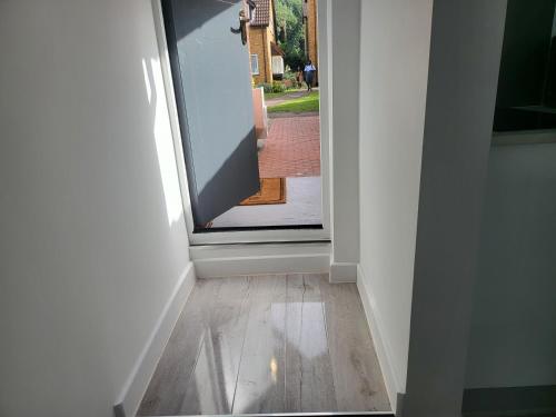 a hallway with a door open to aoyer with a wooden floor at Evabrite Homes in Dartford