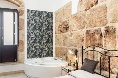 a bathroom with a tub and a stone wall at Morfeo Charming Rooms & Relax in Avola